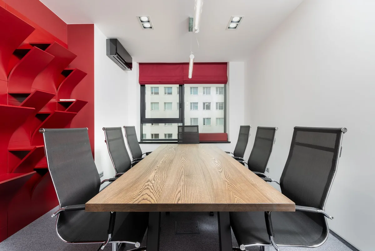 Corporate executive board room with a large wooden table and empty chairs