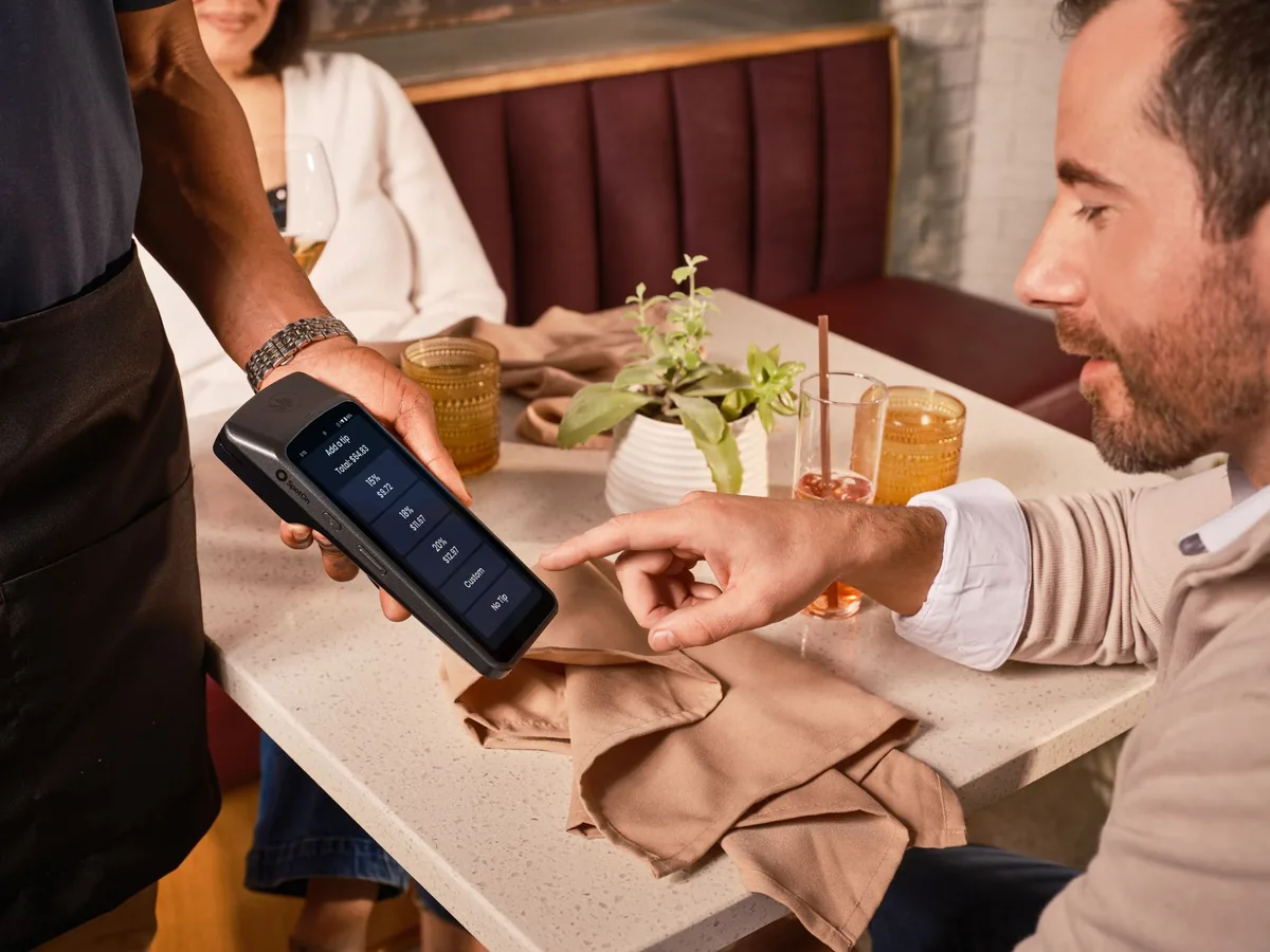 restaurant server holding payment terminal bill