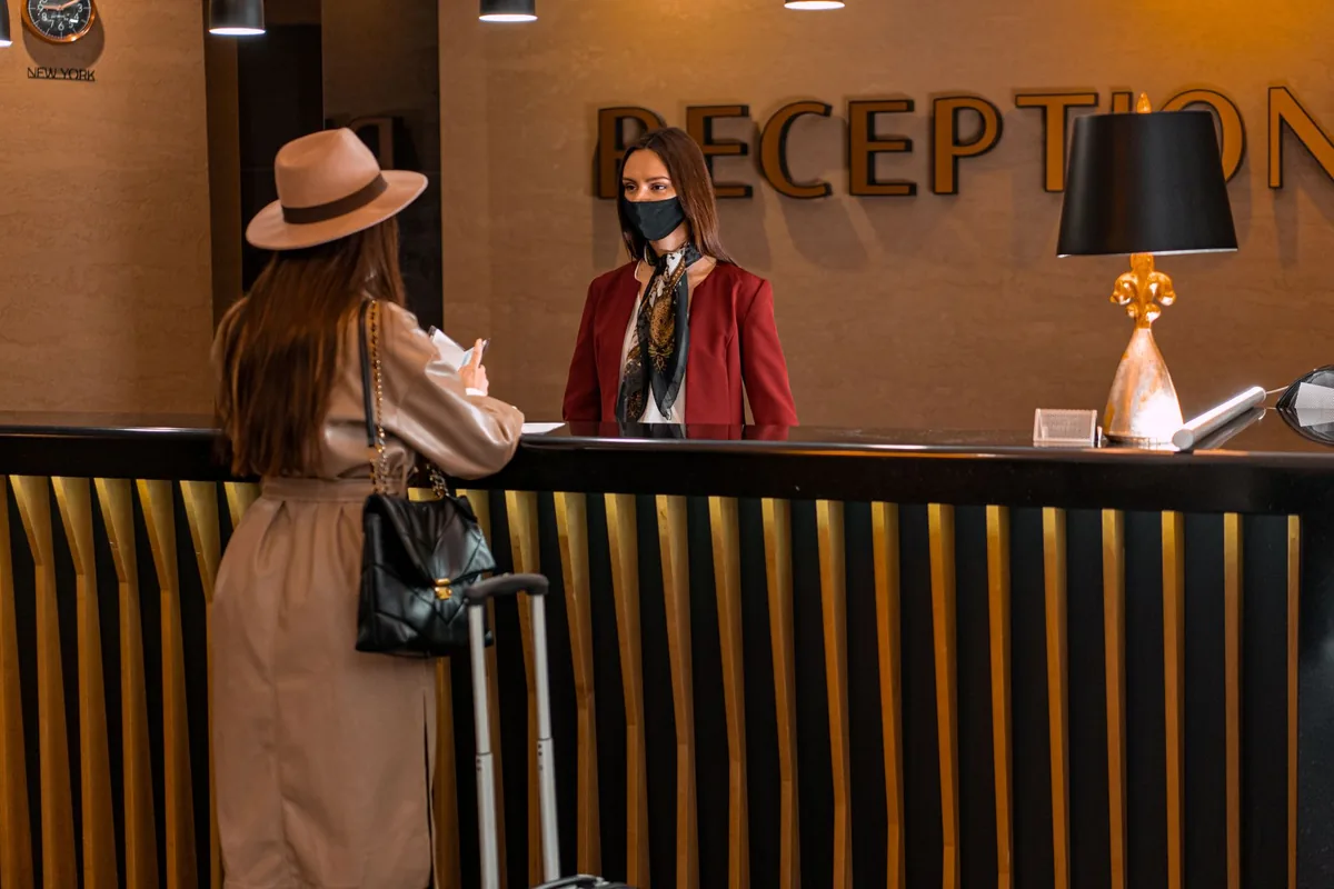 hotel receptionist looking at a property management system screen at the front desk