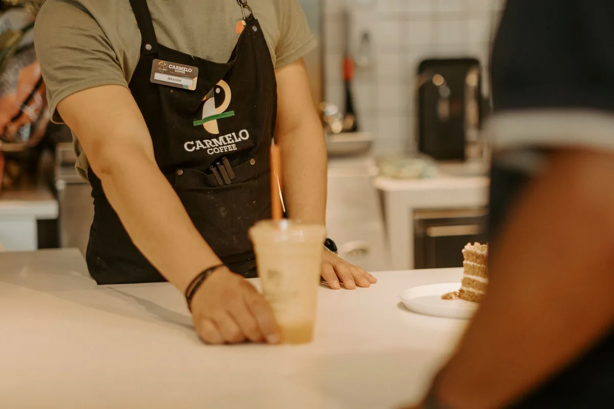 barista handing a custom iced coffee to a guest over a counter
