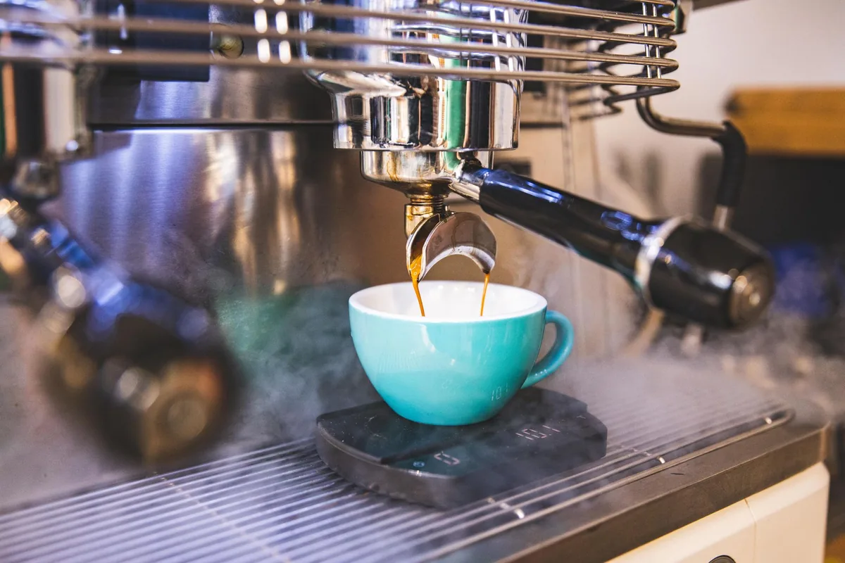 close up of an automated espresso machine dispensing coffee into a ceramic cup
