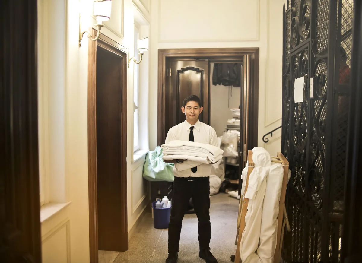 hotel housekeeping staff pushing cleaning cart in corridor