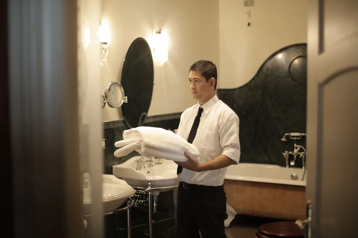 hotel housekeeper cleaning guest room bathroom