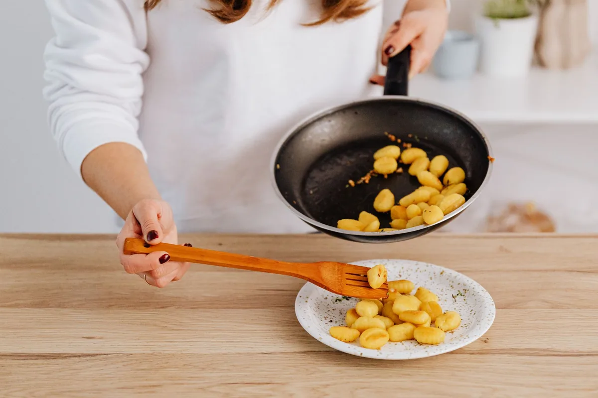 chef plating pasta kitchen counter