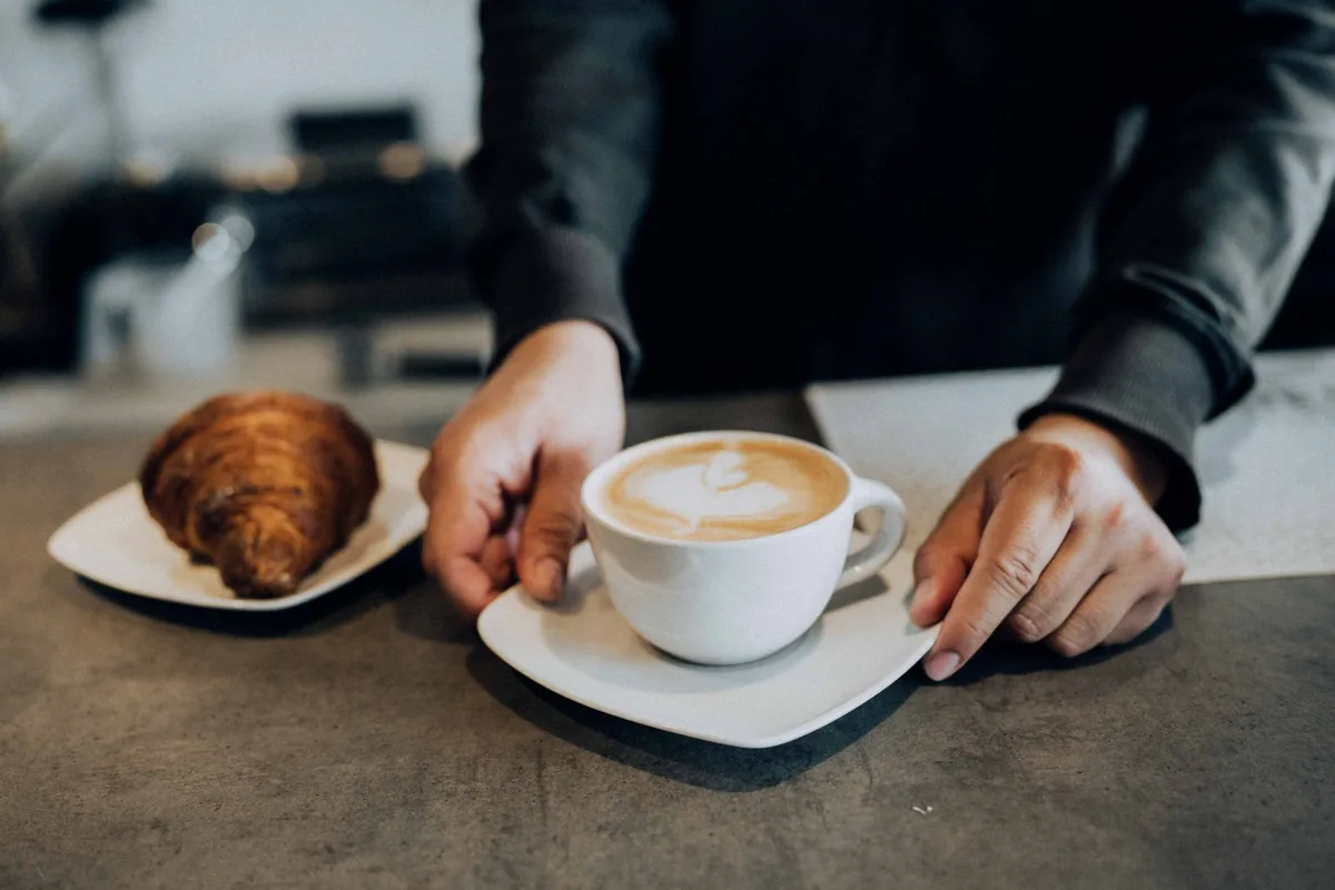 barista preparing espresso drinks with fresh pastries on display