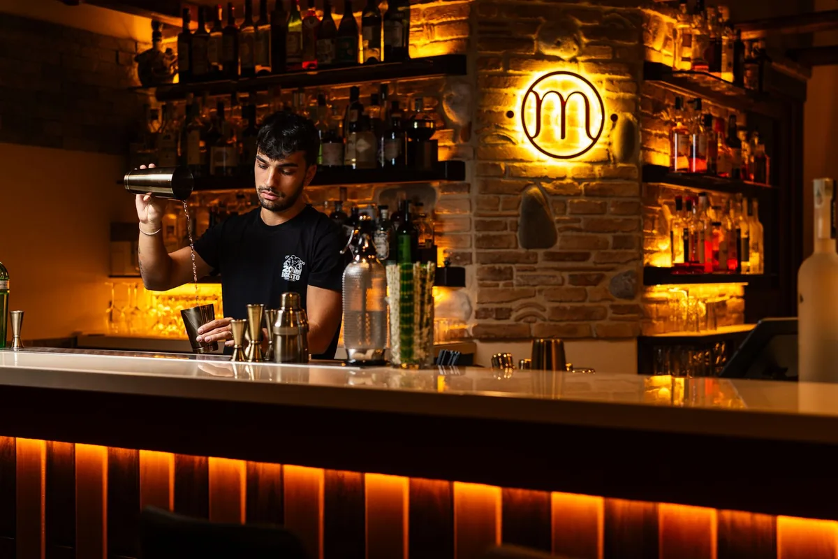 bartender mixing cocktails in a dimly lit lounge with vintage photographs