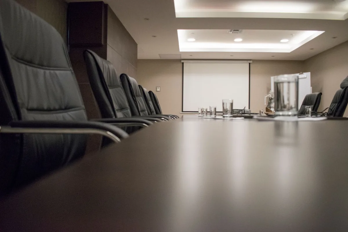 corporate boardroom table with financial documents and empty leather chairs