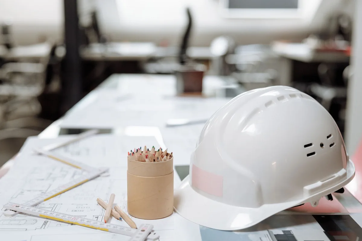 architectural blueprints and hardhats on a construction site table