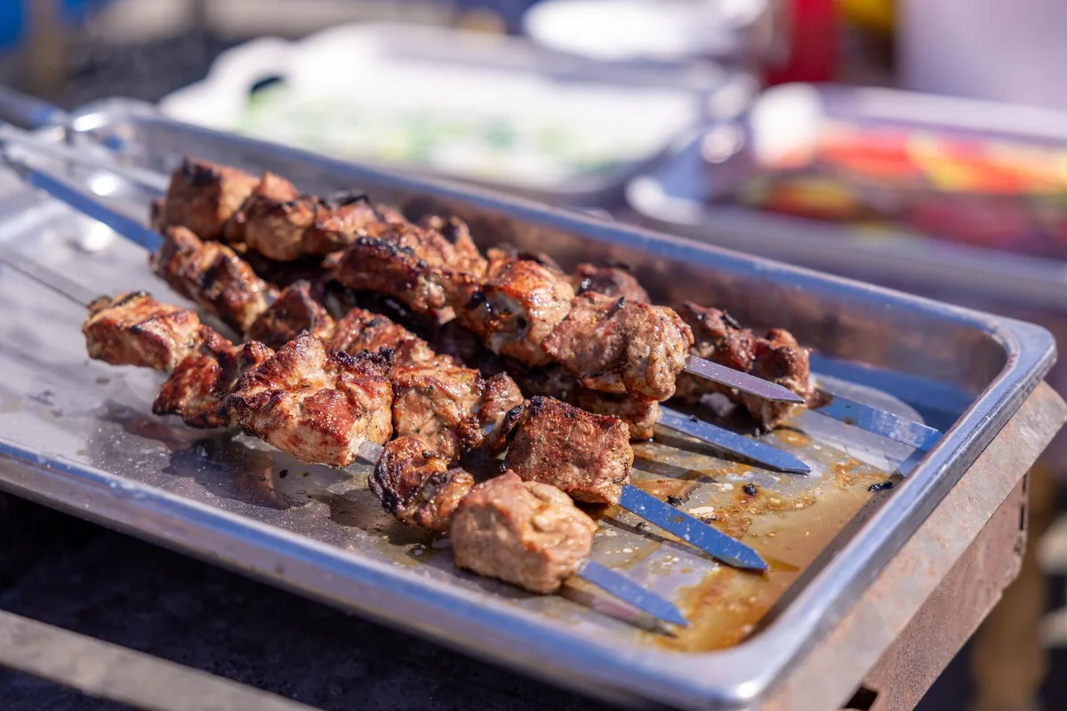 wood-fired grill cooking wagyu beef skewers and whole lobster