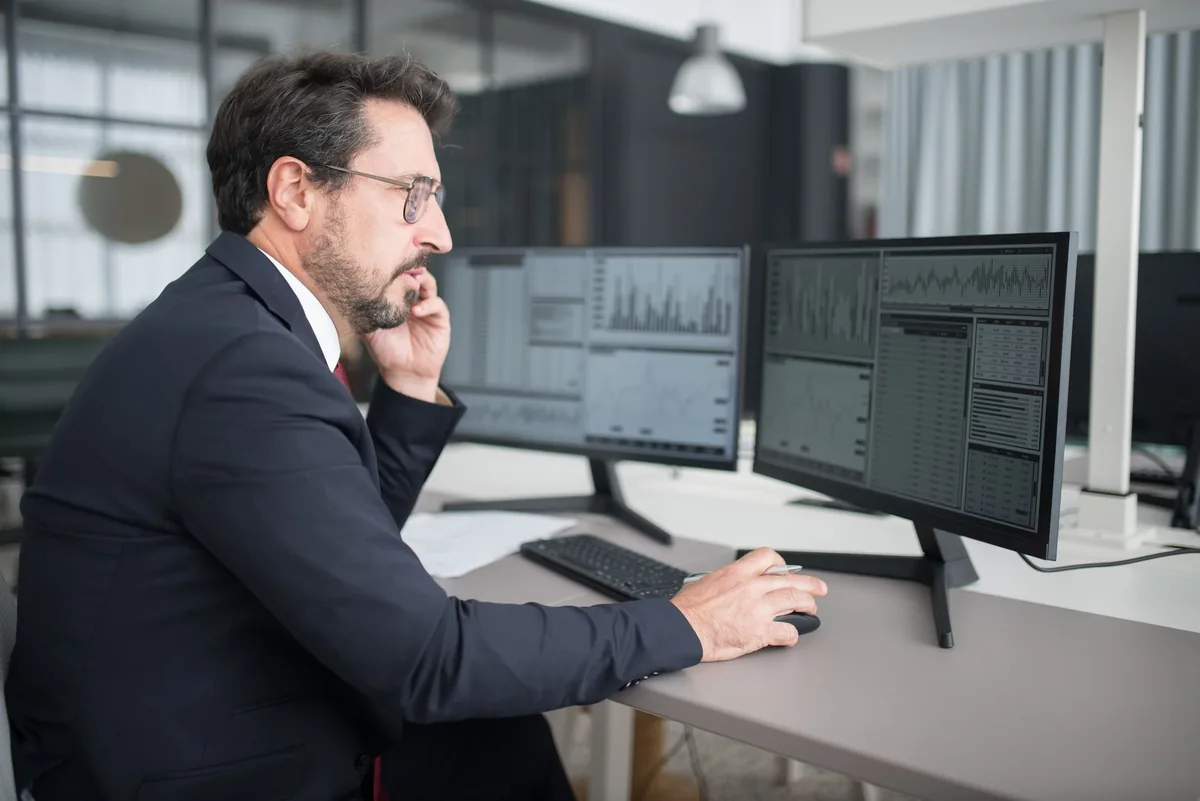 business executive reviewing data on dual monitor screens