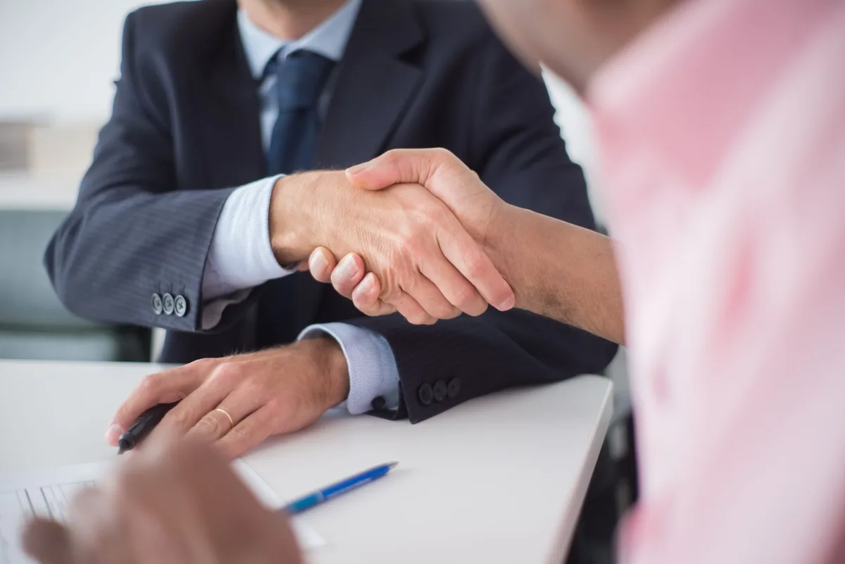 hotel investors shaking hands across meeting table